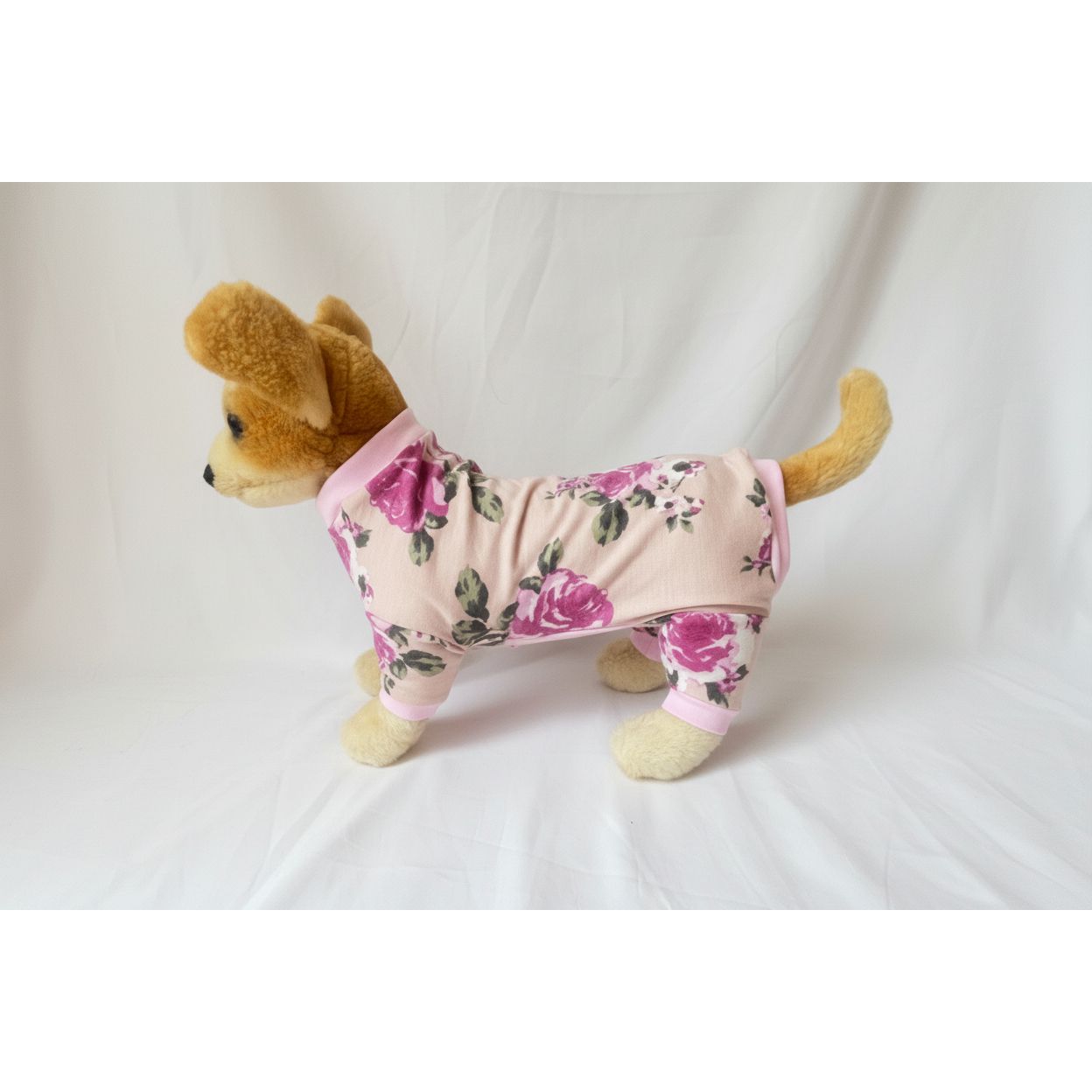 Stuffed dog toy wearing a pink floral outfit on a white background