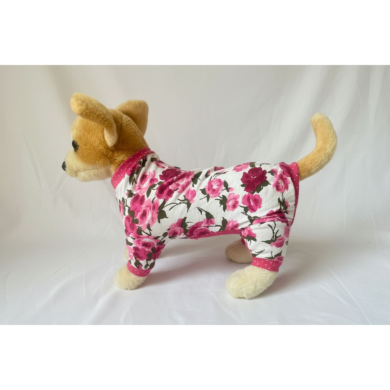 Stuffed dog toy wearing a floral outfit on a white background
