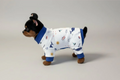 Small dog wearing a white pajama with blue trim on a gray background